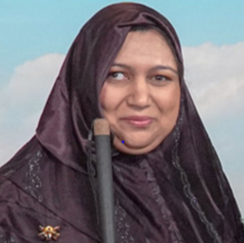 Mariyam is a brown-skinned Muslim woman with a warm smile and brown eyes, wearing a dark purple hijab with silver patterns, and holding a long, white cane. She stands in front of a sky-blue background with clouds.